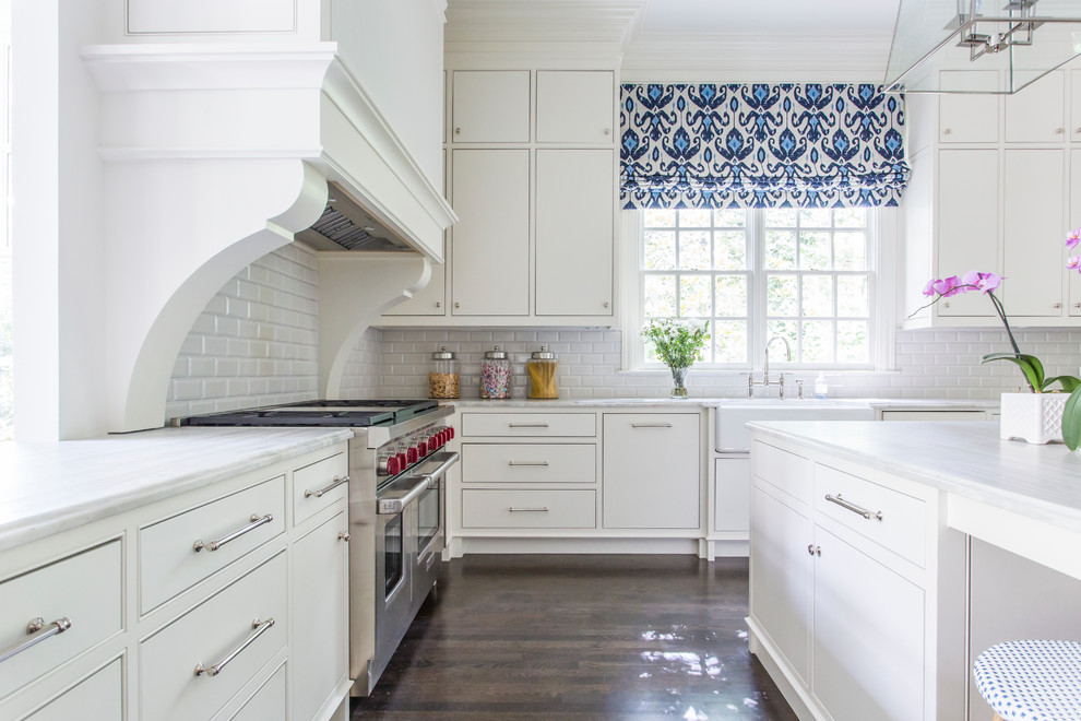 This is an example of a transitional kitchen in Atlanta with a farmhouse sink, flat-panel cabinets, white cabinets, white splashback, subway tile splashback, stainless steel appliances, dark hardwood floors and with island.