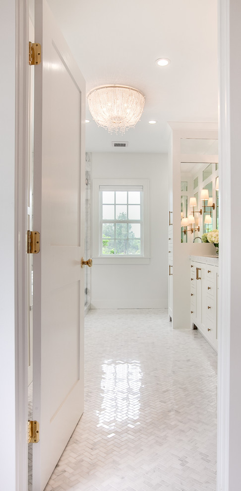 This is an example of a traditional master bathroom in San Diego with white cabinets, a drop-in tub, a corner shower, white tile, marble, white walls, marble floors, an undermount sink, marble benchtops, white floor and white benchtops.