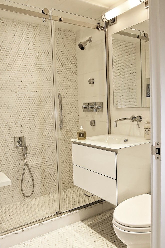 Inspiration for a small contemporary master bathroom in New York with glass-front cabinets, white cabinets, a double shower, white tile, marble, glass benchtops and a sliding shower screen.