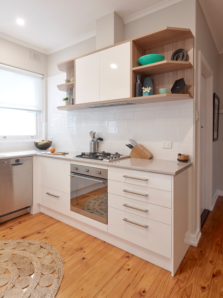 Inspiration for a mid-sized contemporary u-shaped eat-in kitchen in Other with a double-bowl sink, white cabinets, laminate benchtops, white splashback, subway tile splashback, stainless steel appliances, medium hardwood floors, no island, orange floor and beige benchtop.