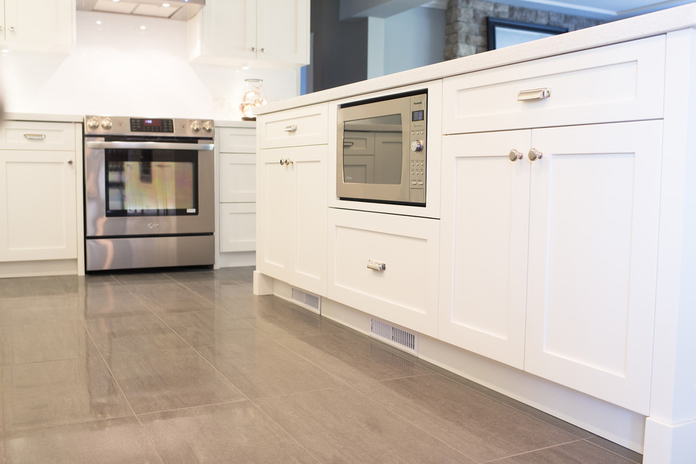 Contemporary l-shaped eat-in kitchen in Vancouver with an undermount sink, shaker cabinets, white cabinets, quartzite benchtops, white splashback, subway tile splashback and stainless steel appliances.