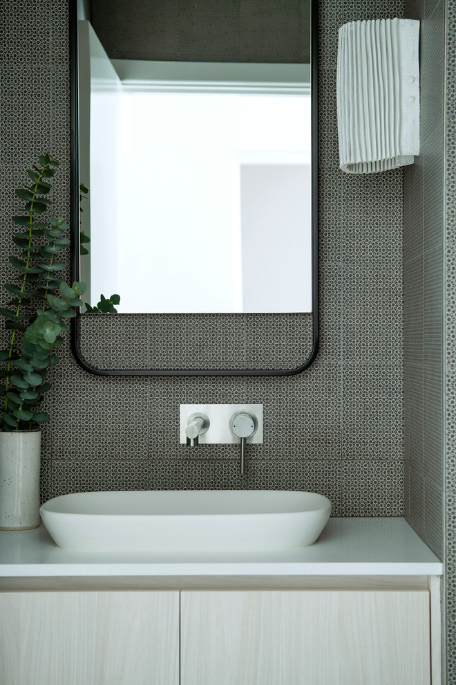 Photo of a mid-sized modern powder room in Perth with white cabinets, black tile, ceramic tile, a vessel sink, engineered quartz benchtops and white benchtops.