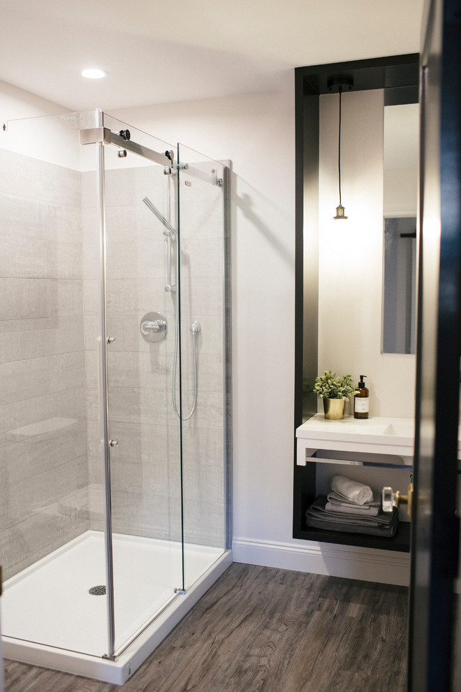 Inspiration for a mid-sized industrial bathroom with a corner shower, gray tile, white walls, dark hardwood floors, an integrated sink, brown floor and a hinged shower door.