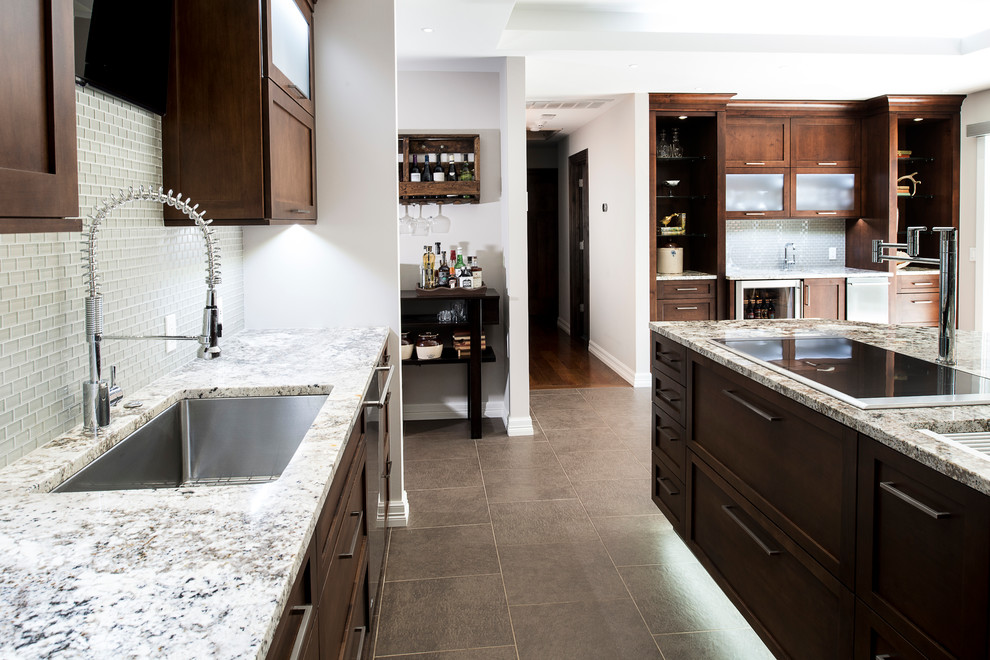 Inspiration for a large transitional ceramic tile and beige floor eat-in kitchen remodel with an undermount sink, shaker cabinets, brown cabinets, granite countertops, stainless steel appliances, an island, white backsplash and glass tile backsplash