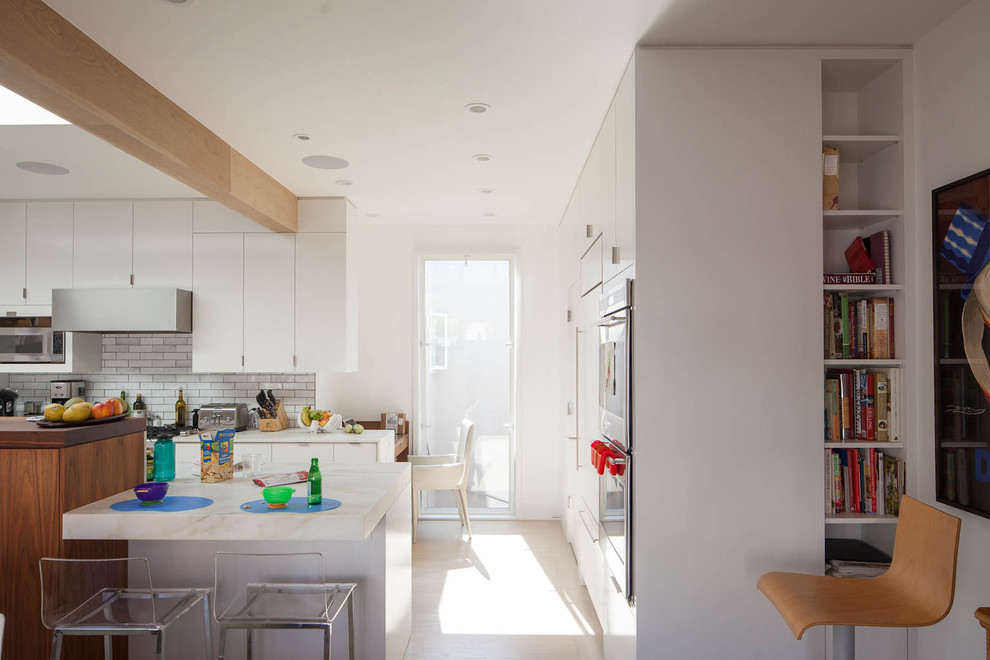 Modern eat-in kitchen in San Francisco with flat-panel cabinets and white cabinets.