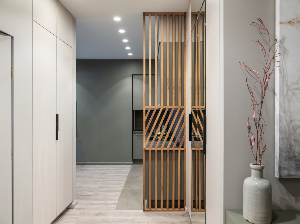 Inspiration pour une entrée design avec un couloir, un mur gris, un sol en carrelage de porcelaine et une porte grise.