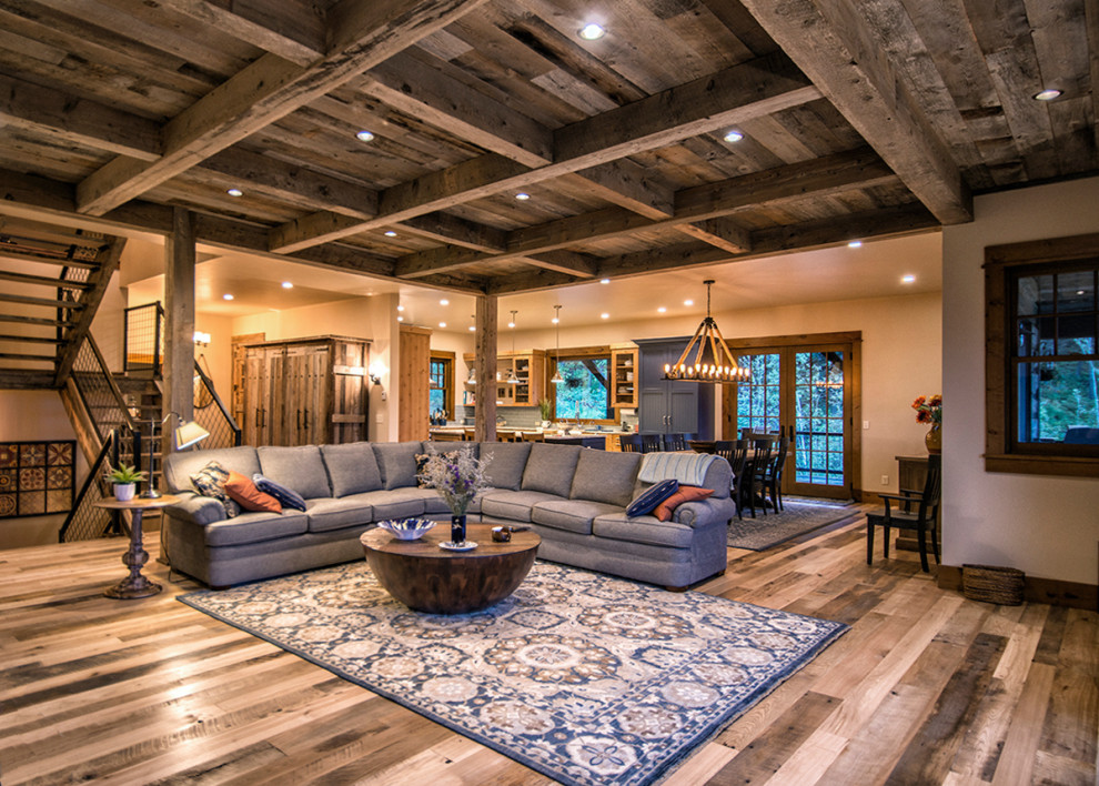 Mid-sized mountain style open concept medium tone wood floor, multicolored floor, exposed beam and wood wall family room photo in Other with beige walls, a media wall, a standard fireplace and a stone fireplace