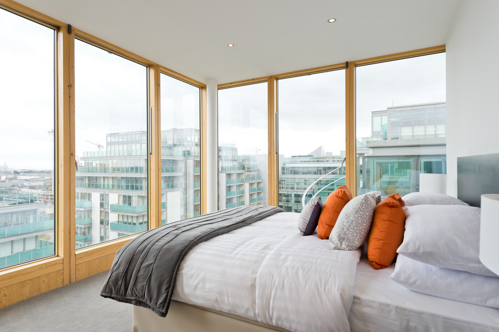 This is an example of a contemporary guest bedroom in Dublin with white walls, carpet and grey floor.