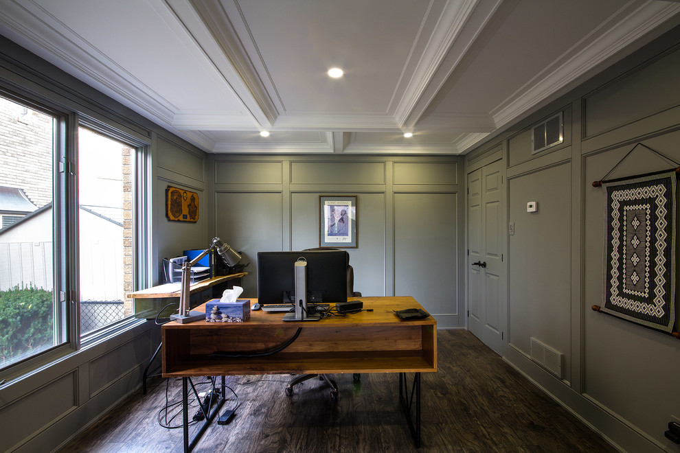 This is an example of a mid-sized traditional home office in Toronto with a library, grey walls, laminate floors, a standard fireplace and a wood fireplace surround.