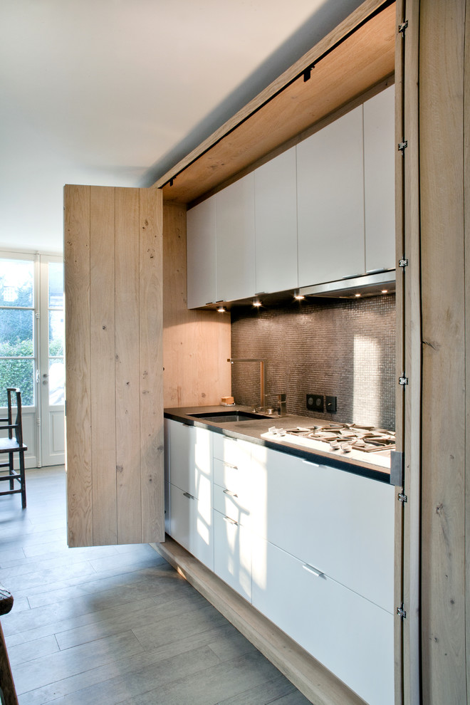 This is an example of a country single-wall open plan kitchen in Paris with flat-panel cabinets, brown splashback, mosaic tile splashback, laminate floors, with island, brown floor, brown benchtop and recessed.