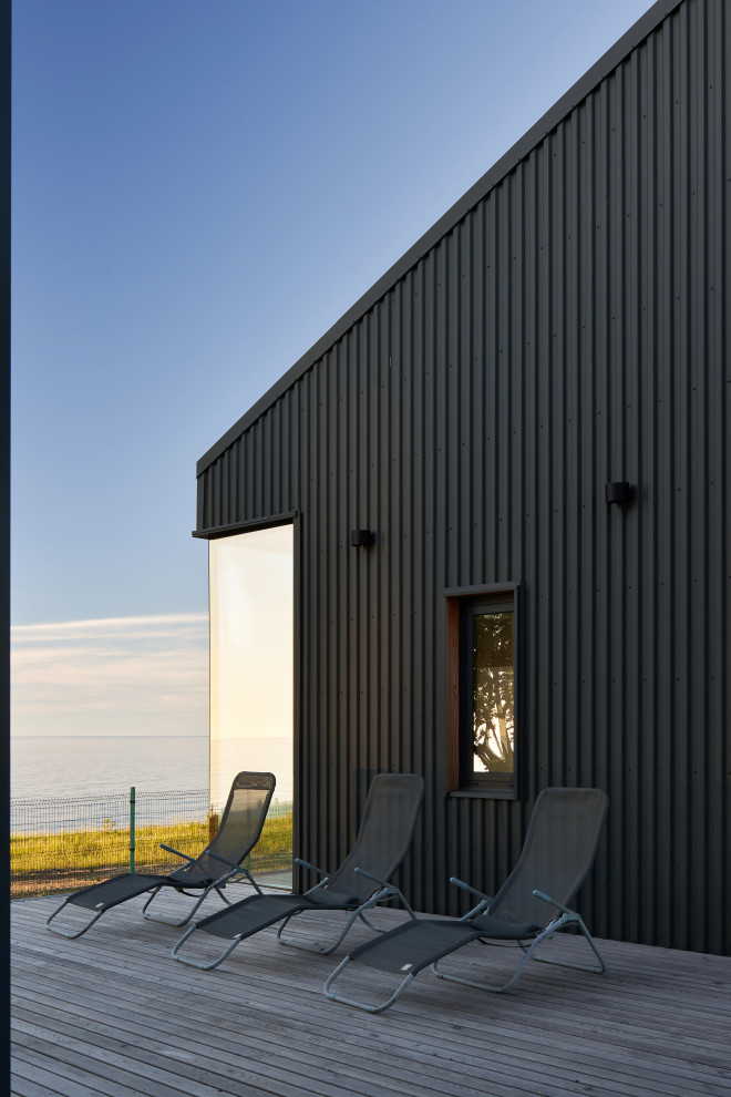 Aménagement d'une façade de maison métallique et grise scandinave de plain-pied avec un toit gris.