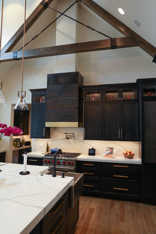 Large transitional u-shaped light wood floor open concept kitchen photo with a farmhouse sink, flat-panel cabinets, dark wood cabinets, quartz countertops, white backsplash, quartz backsplash, stainless steel appliances, an island and white countertops