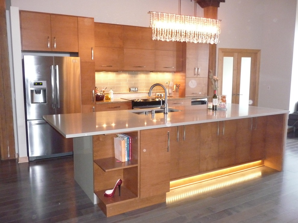 Photo of a mid-sized modern galley eat-in kitchen in Milwaukee with an undermount sink, flat-panel cabinets, medium wood cabinets, quartz benchtops, beige splashback, glass tile splashback, stainless steel appliances, medium hardwood floors and with island.