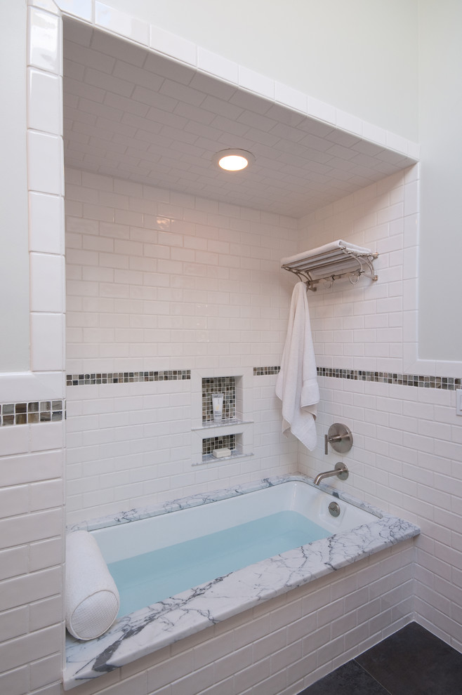 This is an example of a mid-sized traditional master bathroom in New York with subway tile, white walls, an undermount tub, white tile, porcelain floors, grey floor and a niche.