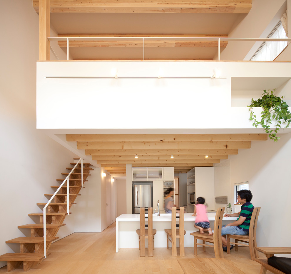 Modern u-shaped open plan kitchen in Tokyo with flat-panel cabinets, white cabinets, stainless steel appliances, light hardwood floors and a peninsula.