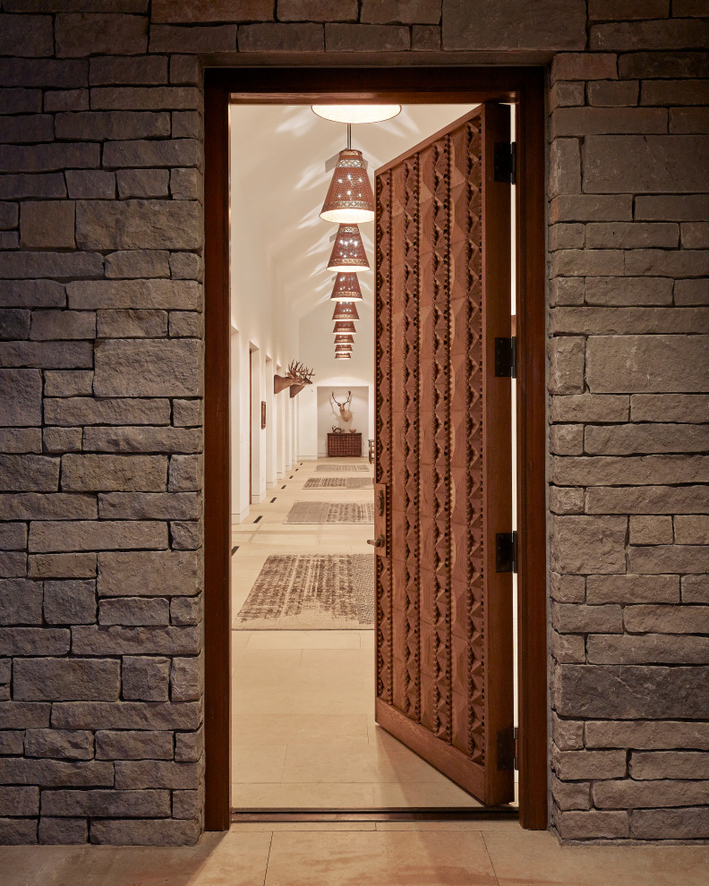 Example of a large mountain style ceramic tile, beige floor, vaulted ceiling and brick wall front door design in Austin with white walls and a medium wood front door