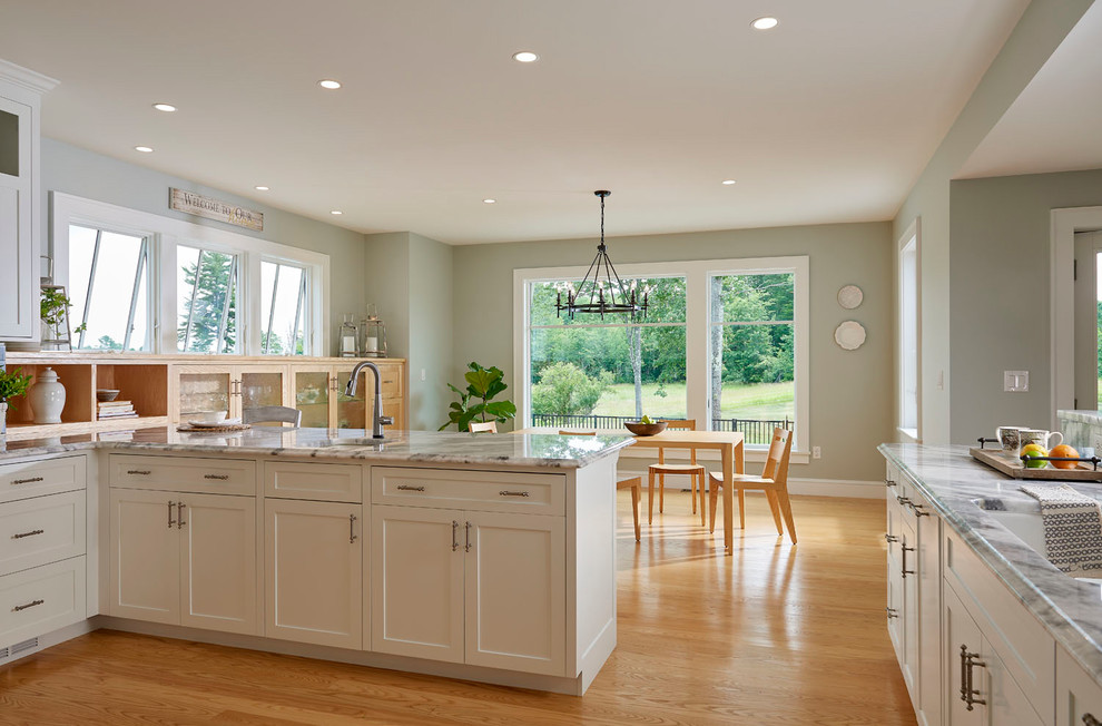Design ideas for a mid-sized country u-shaped eat-in kitchen in Portland Maine with an undermount sink, recessed-panel cabinets, white cabinets, quartzite benchtops, white splashback, stainless steel appliances, light hardwood floors, a peninsula, yellow floor and white benchtop.