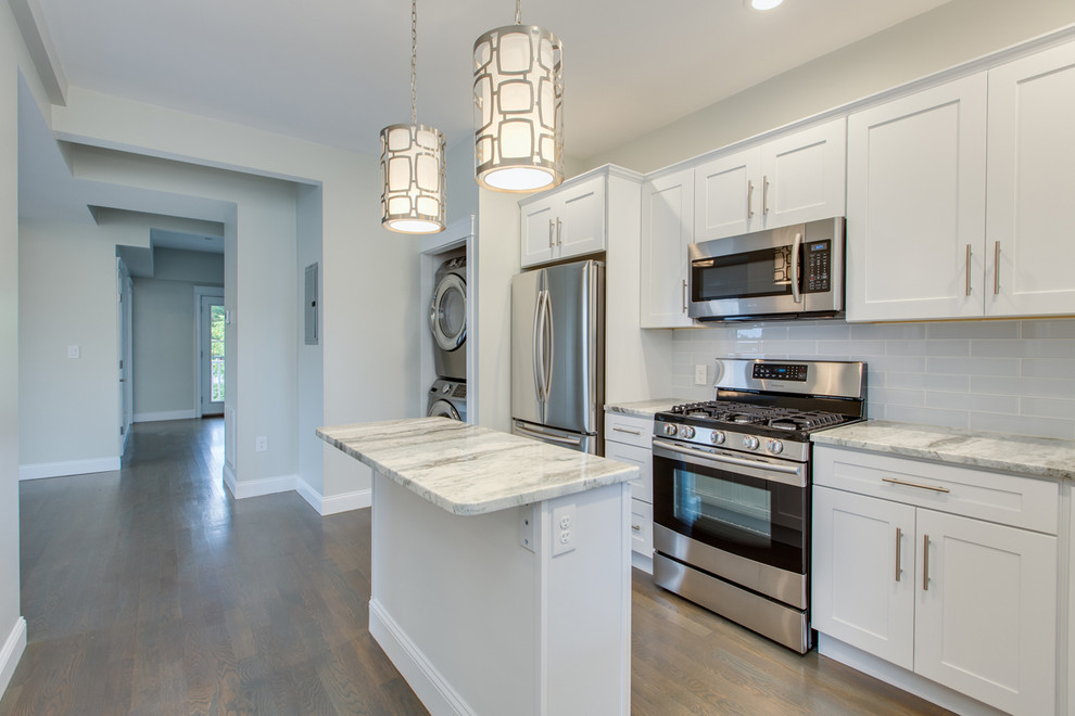 Inspiration for a mid-sized transitional l-shaped dark wood floor and brown floor enclosed kitchen remodel in Boston with an undermount sink, shaker cabinets, white cabinets, marble countertops, gray backsplash, subway tile backsplash, stainless steel appliances, an island and white countertops