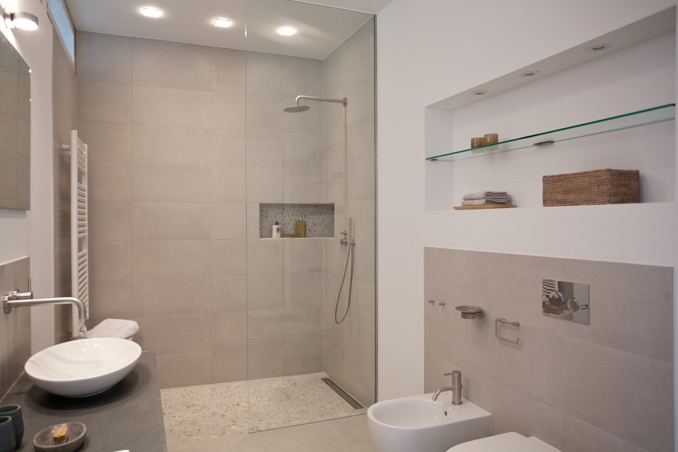 Mid-sized contemporary 3/4 bathroom in Berlin with a curbless shower, a wall-mount toilet, gray tile, ceramic tile, white walls, pebble tile floors and a vessel sink.