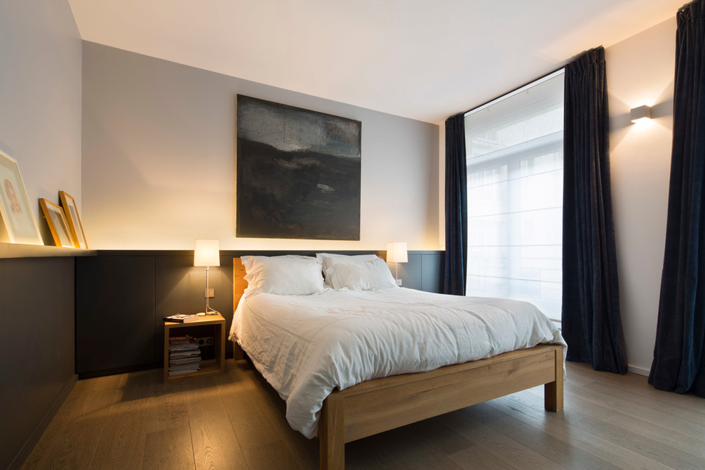 Inspiration pour une grande chambre parentale design avec un mur gris et parquet clair.