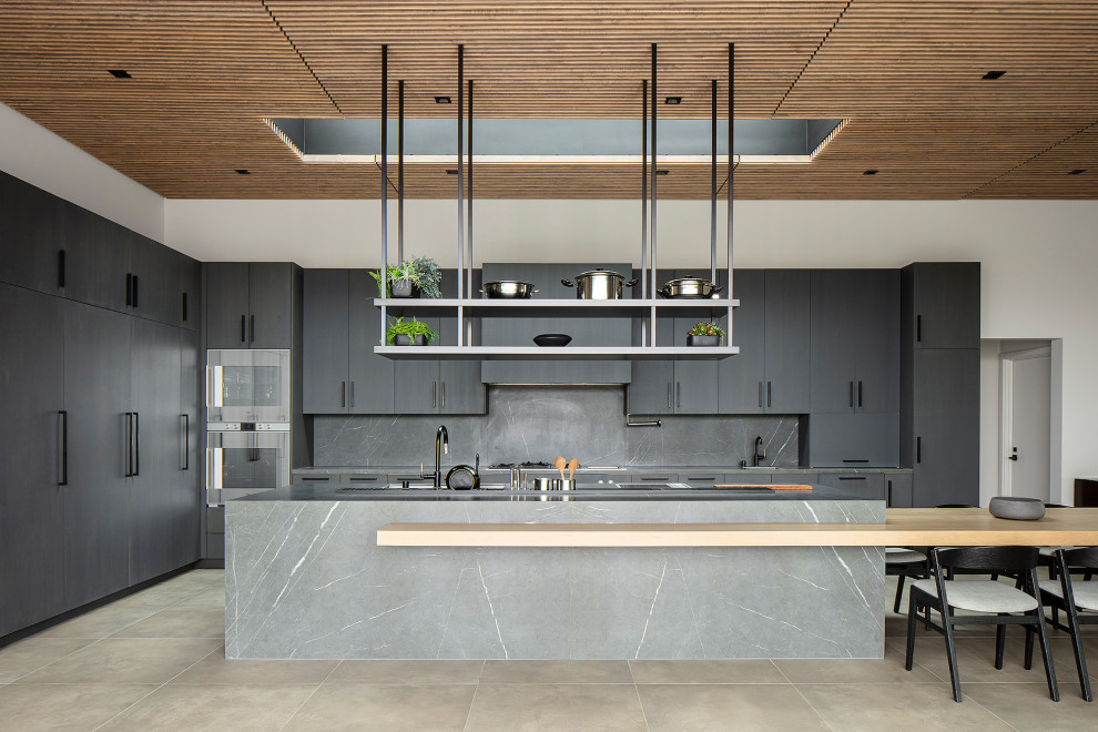 Inspiration for a huge contemporary l-shaped ceramic tile, gray floor and wood ceiling open concept kitchen remodel in Los Angeles with flat-panel cabinets, gray cabinets, an island, a double-bowl sink, marble countertops, gray backsplash, stone slab backsplash, stainless steel appliances and gray countertops