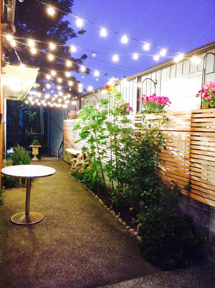 Small side yard patio in Seattle with concrete slab and an awning.