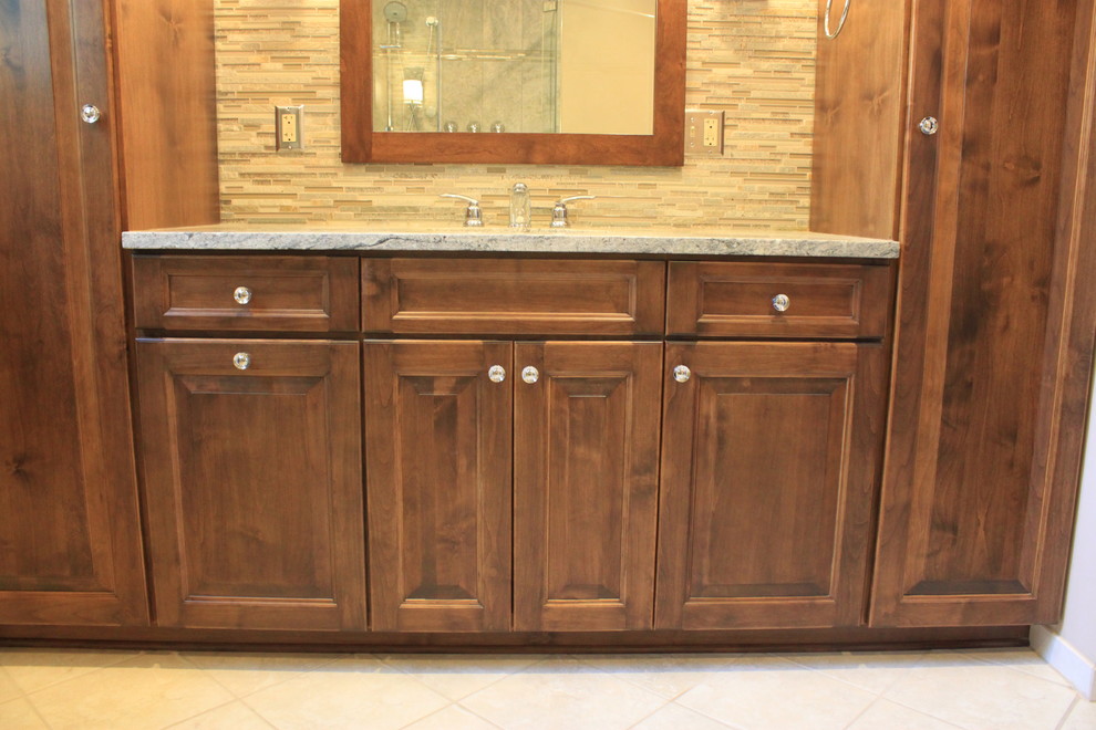 This is an example of a large transitional master bathroom in Other with raised-panel cabinets, dark wood cabinets, granite benchtops, multi-coloured tile, an alcove shower, a two-piece toilet, matchstick tile, beige walls, linoleum floors and an undermount sink.