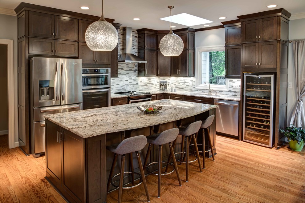 Design ideas for a mid-sized contemporary l-shaped eat-in kitchen in Raleigh with an undermount sink, shaker cabinets, dark wood cabinets, granite benchtops, metallic splashback, stone tile splashback, stainless steel appliances, medium hardwood floors, with island and brown floor.