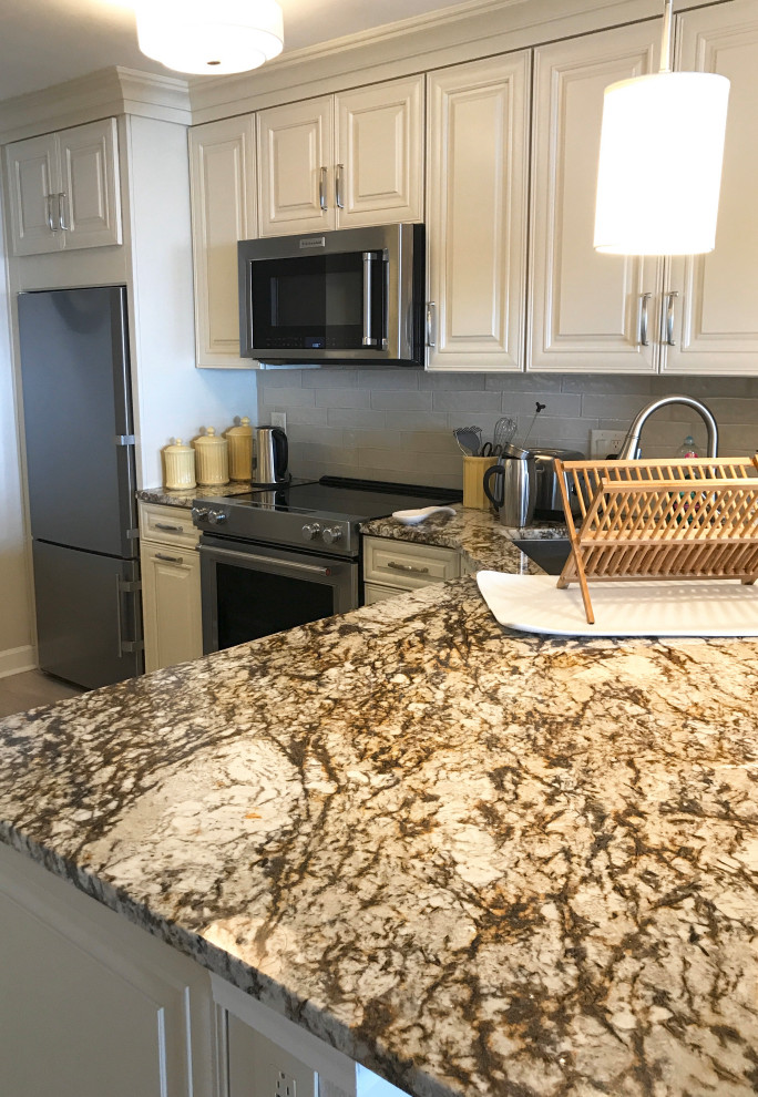 This is an example of a mid-sized traditional l-shaped eat-in kitchen in Jacksonville with a single-bowl sink, recessed-panel cabinets, beige cabinets, granite benchtops, beige splashback, ceramic splashback, stainless steel appliances, laminate floors, a peninsula, grey floor and beige benchtop.