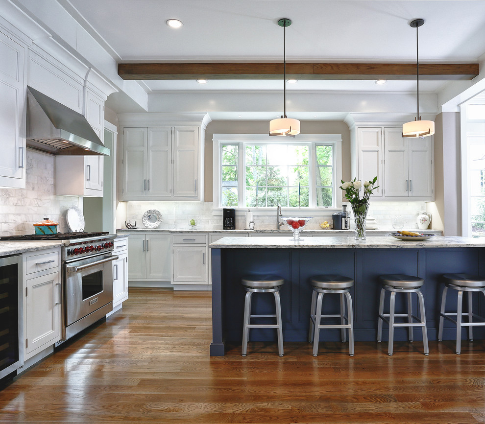 Inspiration for a large traditional u-shaped eat-in kitchen in New York with shaker cabinets, white cabinets, white splashback, stainless steel appliances, medium hardwood floors, with island, an undermount sink, marble benchtops, marble splashback and brown floor.