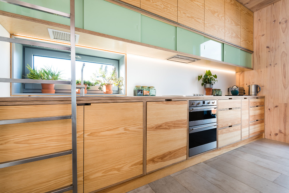 This is an example of a mid-sized midcentury galley open plan kitchen in Edinburgh with a farmhouse sink, light wood cabinets, stainless steel appliances and with island.