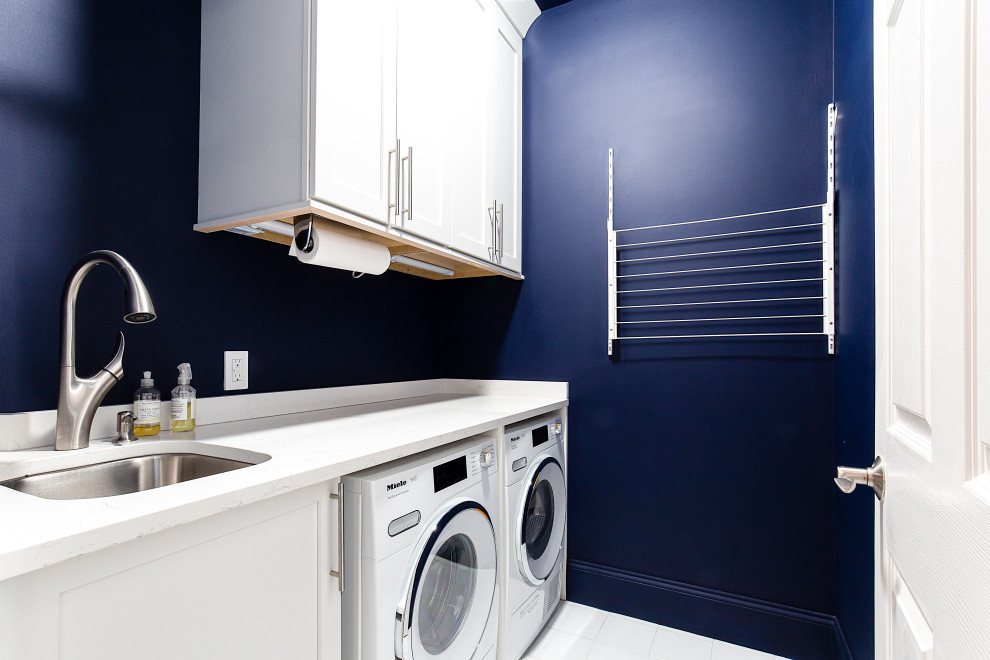 Design ideas for a small eclectic single-wall dedicated laundry room in Atlanta with a single-bowl sink, shaker cabinets, white cabinets, quartz benchtops, blue walls, a side-by-side washer and dryer and white benchtop.