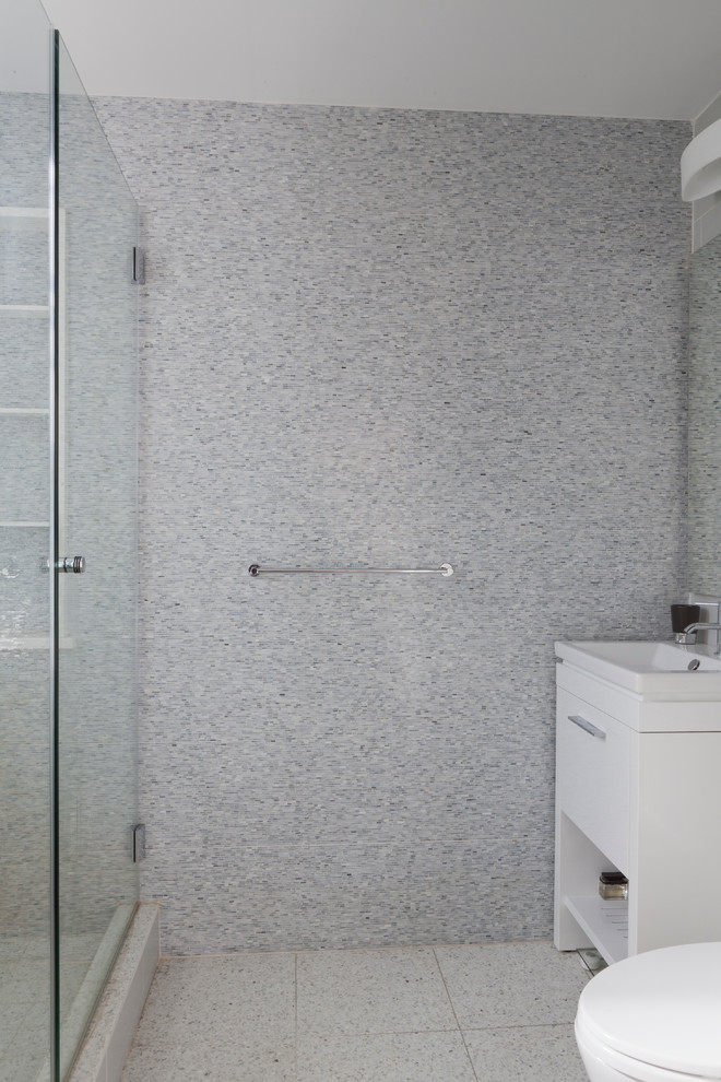 Small modern master bathroom in New York with flat-panel cabinets, white cabinets, an alcove shower, a one-piece toilet, blue tile and glass tile.