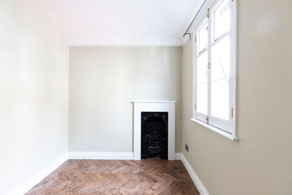 Bild på ett litet vintage gästrum, med vita väggar, mörkt trägolv, en standard öppen spis, en spiselkrans i gips och brunt golv
