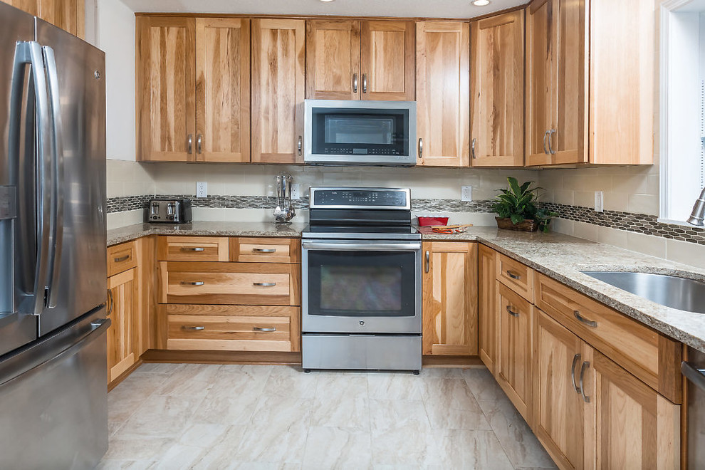 Mid-sized transitional u-shaped enclosed kitchen photo with an undermount sink, shaker cabinets, light wood cabinets, quartz countertops, white backsplash, subway tile backsplash, stainless steel appliances and no island