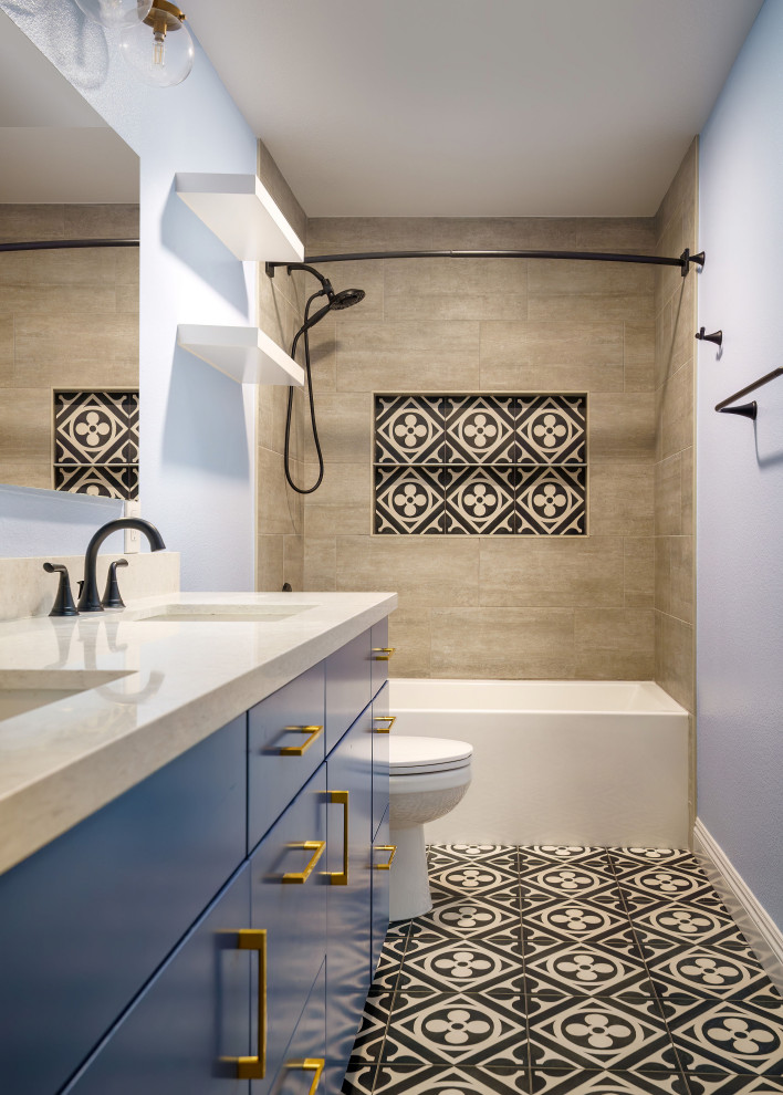 This is an example of a medium sized beach style family bathroom in Los Angeles with flat-panel cabinets, blue cabinets, an alcove bath, a two-piece toilet, beige tiles, ceramic tiles, blue walls, cement flooring, a submerged sink, engineered stone worktops, multi-coloured floors, white worktops, double sinks and a built in vanity unit.