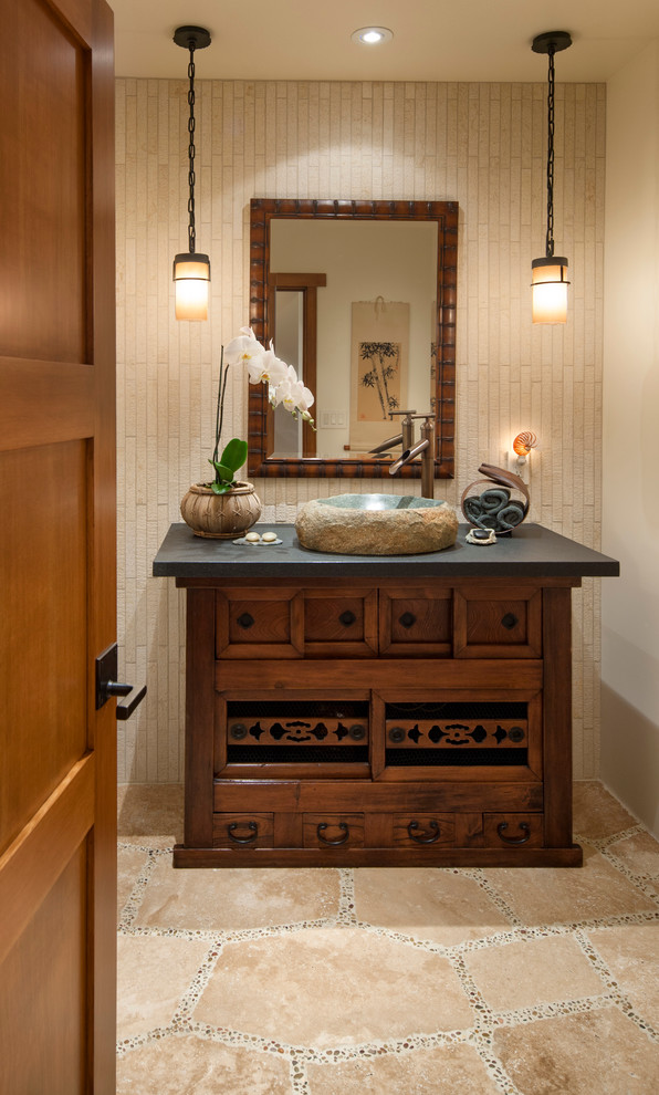 Design ideas for a mid-sized asian powder room in Santa Barbara with a vessel sink, furniture-like cabinets, granite benchtops, beige tile, beige walls, travertine floors and dark wood cabinets.
