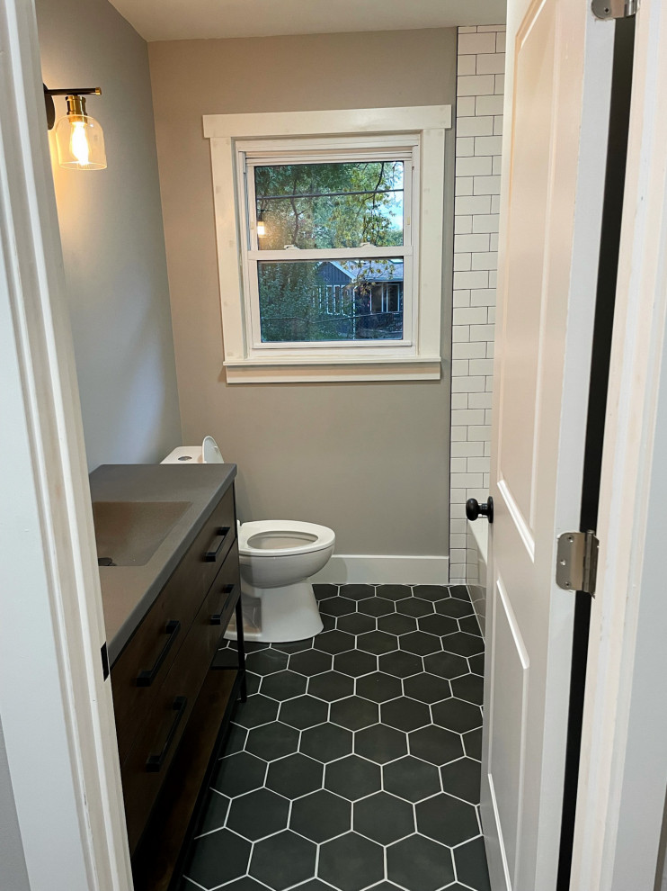 Photo of a medium sized modern ensuite bathroom in Detroit with shaker cabinets, dark wood cabinets, a built-in bath, a shower/bath combination, a one-piece toilet, white tiles, metro tiles, grey walls, porcelain flooring, a built-in sink, concrete worktops, black floors, a shower curtain, grey worktops, a wall niche, a single sink and a freestanding vanity unit.
