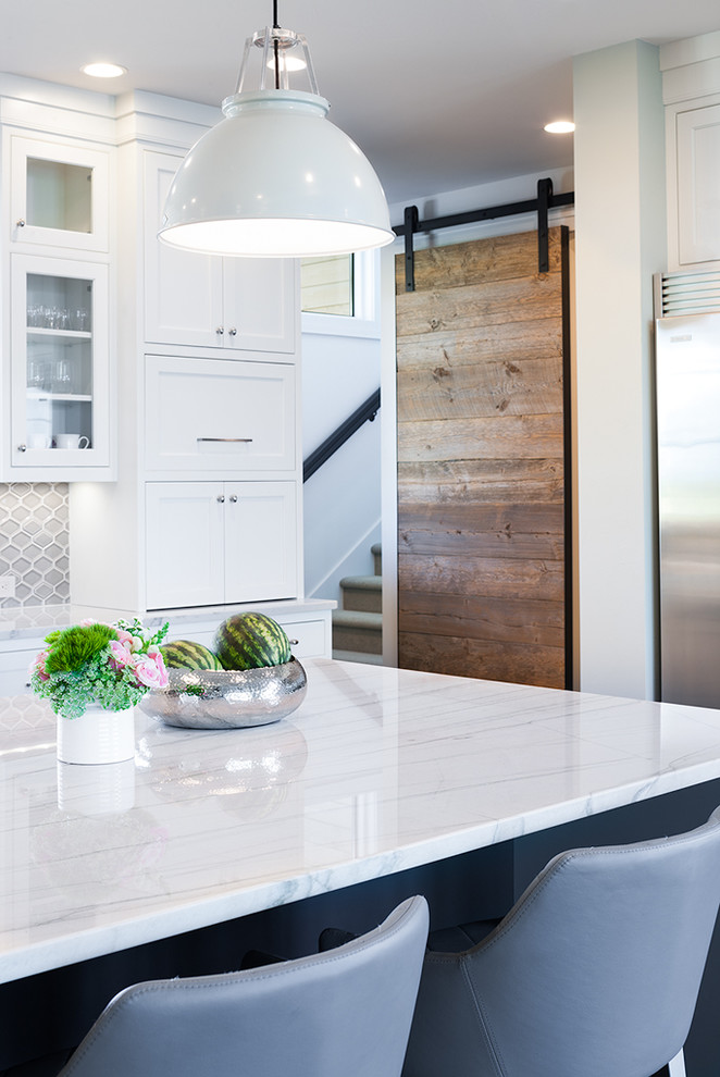 Example of a large transitional l-shaped dark wood floor open concept kitchen design with a farmhouse sink, shaker cabinets, white cabinets, quartzite countertops, gray backsplash, porcelain backsplash, stainless steel appliances and an island