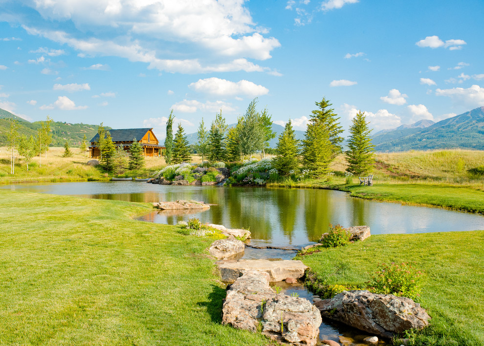 Photo of a large country backyard full sun garden in Denver with with pond.