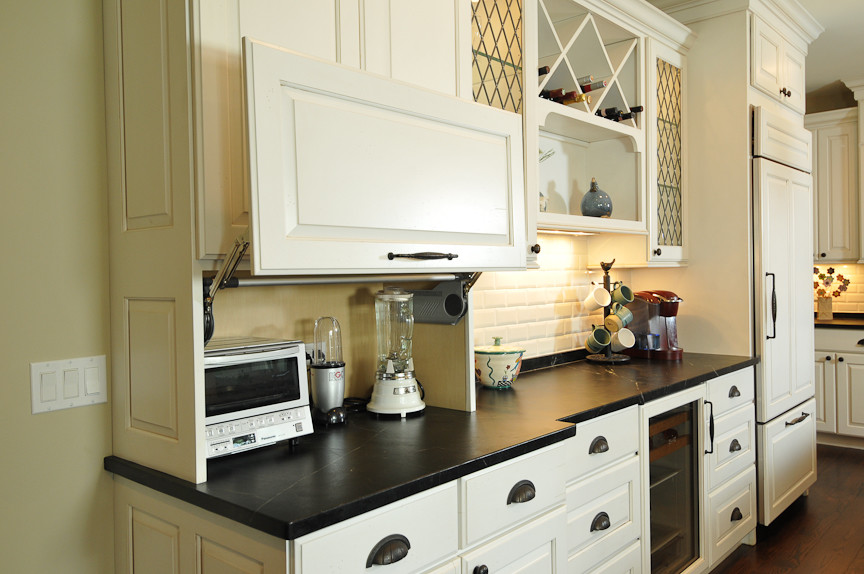 Inspiration for a rustic l-shaped eat-in kitchen remodel in Chicago with a farmhouse sink, raised-panel cabinets, white cabinets, soapstone countertops, white backsplash, subway tile backsplash and paneled appliances