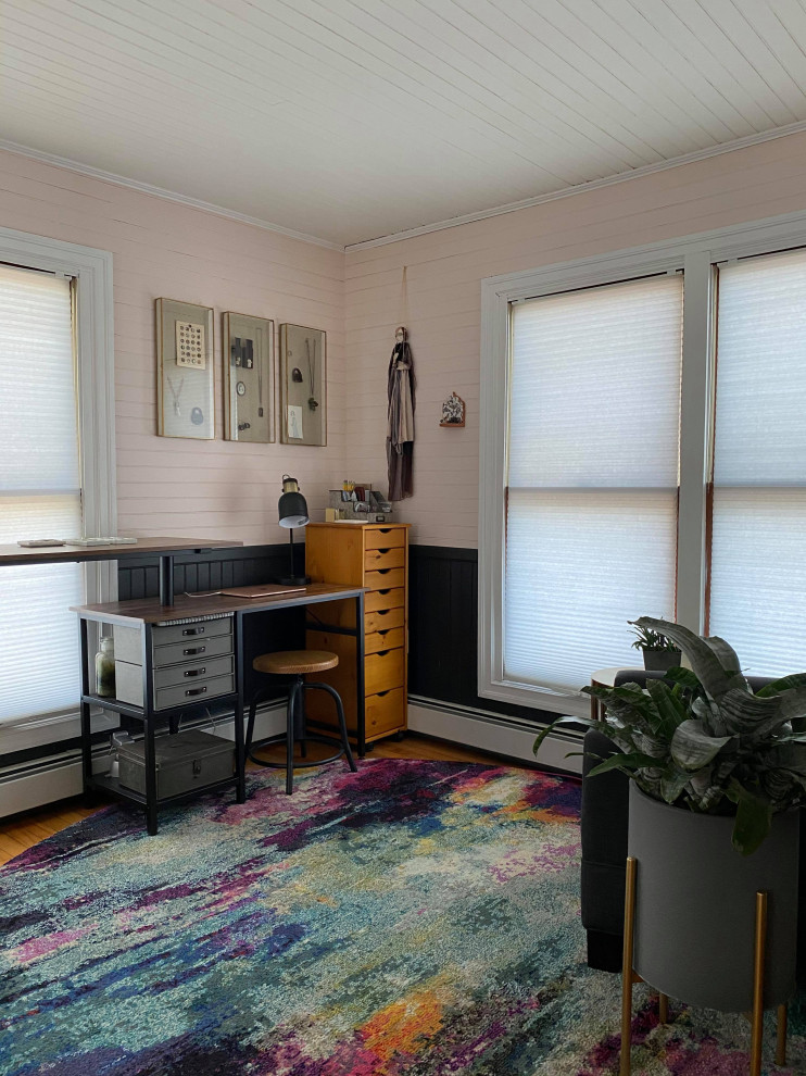 Foto på ett litet industriellt hemmastudio, med rosa väggar, mellanmörkt trägolv och ett fristående skrivbord