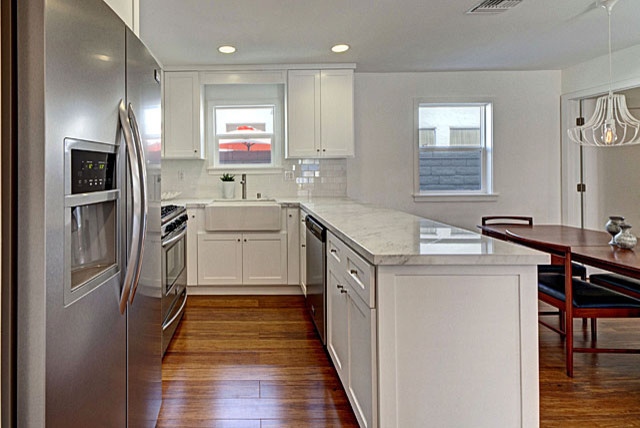 Small country u-shaped eat-in kitchen in Los Angeles with a farmhouse sink, shaker cabinets, white cabinets, marble benchtops, white splashback, ceramic splashback, stainless steel appliances and bamboo floors.