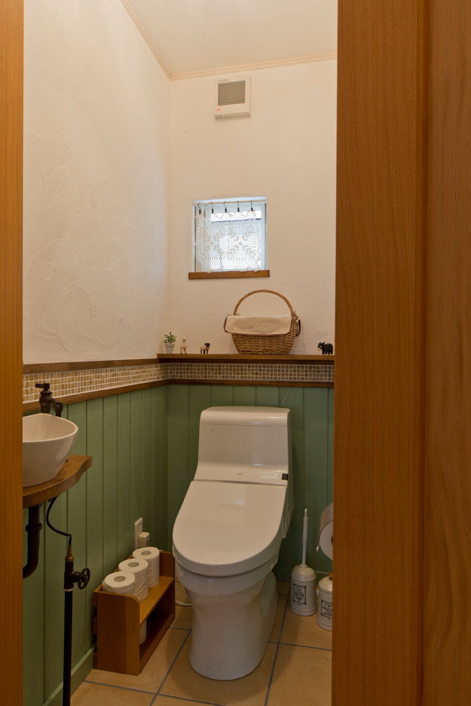Photo of a country powder room in Other with a vessel sink, beige floor and a one-piece toilet.