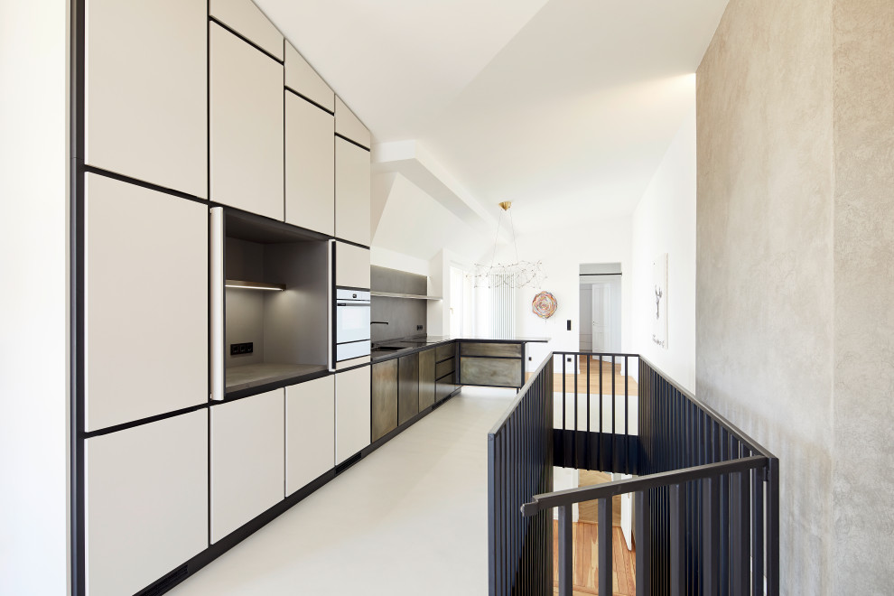 Offene, Große Moderne grifflose Küche in L-Form mit Unterbauwaschbecken, flächenbündigen Schrankfronten, braunen Schränken, Granit-Arbeitsplatte, Küchenrückwand in Grau, Betonboden, Halbinsel, beigem Boden und grauer Arbeitsplatte in Berlin