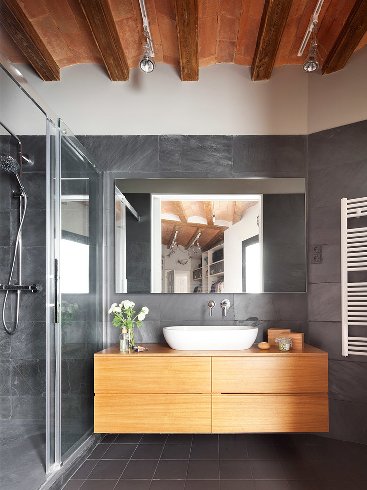Inspiration for a small contemporary 3/4 bathroom in Barcelona with a vessel sink, flat-panel cabinets, light wood cabinets, an alcove shower, gray tile, grey walls, ceramic floors, stone slab and wood benchtops.