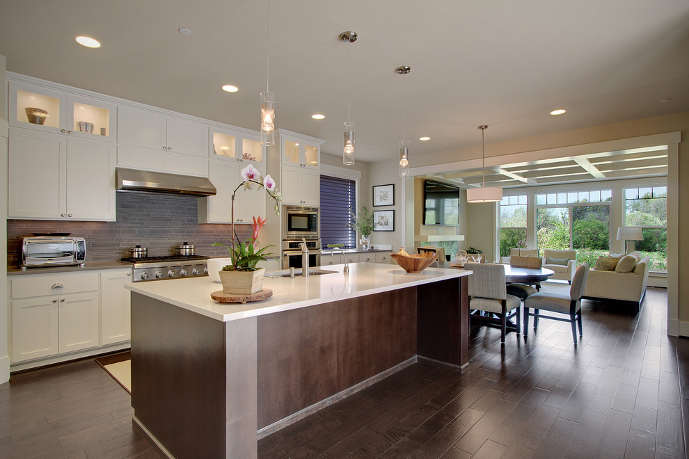 This is an example of a large transitional galley eat-in kitchen in Seattle with an undermount sink, recessed-panel cabinets, white cabinets, grey splashback, matchstick tile splashback, stainless steel appliances, dark hardwood floors, brown floor, quartz benchtops, with island and grey benchtop.