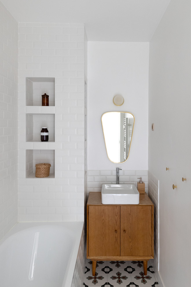 Design ideas for a small contemporary kids bathroom in Paris with beaded inset cabinets, light wood cabinets, an undermount tub, white tile, subway tile, white walls, cement tiles, a drop-in sink, wood benchtops, multi-coloured floor and brown benchtops.