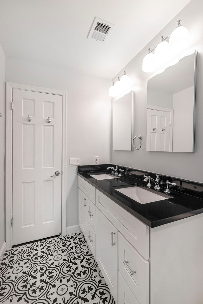 Пример оригинального дизайна: главная ванная комната среднего размера в стиле кантри с фасадами в стиле шейкер, белыми фасадами, душем в нише, раздельным унитазом, белой плиткой, плиткой кабанчик, серыми стенами, полом из керамогранита, врезной раковиной, столешницей из искусственного кварца, разноцветным полом, душем с раздвижными дверями, черной столешницей, нишей, тумбой под две раковины и встроенной тумбой