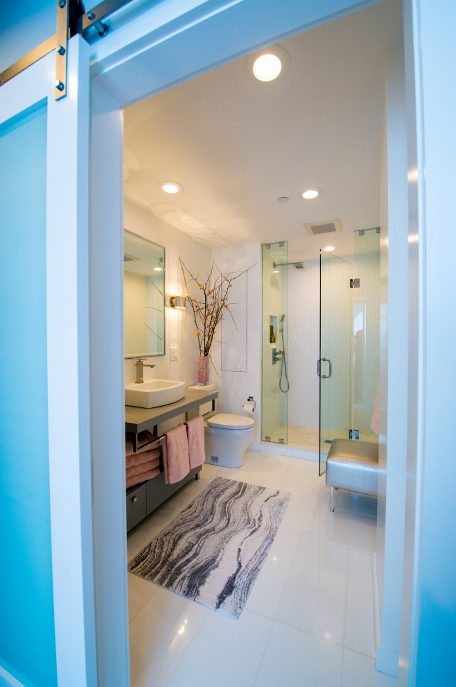 This is an example of a mid-sized modern master bathroom in Boston with open cabinets, grey cabinets, an alcove shower, a one-piece toilet, white tile, glass tile, white walls, porcelain floors, a vessel sink, solid surface benchtops, white floor, a hinged shower door and grey benchtops.